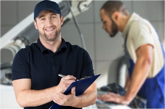 Image of a mechanic holding a clipboard in an auto shop.