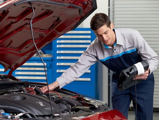 Image of a technician running a test on the engine of a Mazda vehicle.
