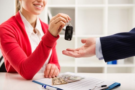 Image of a woman in a red sweater handing a man car keys.